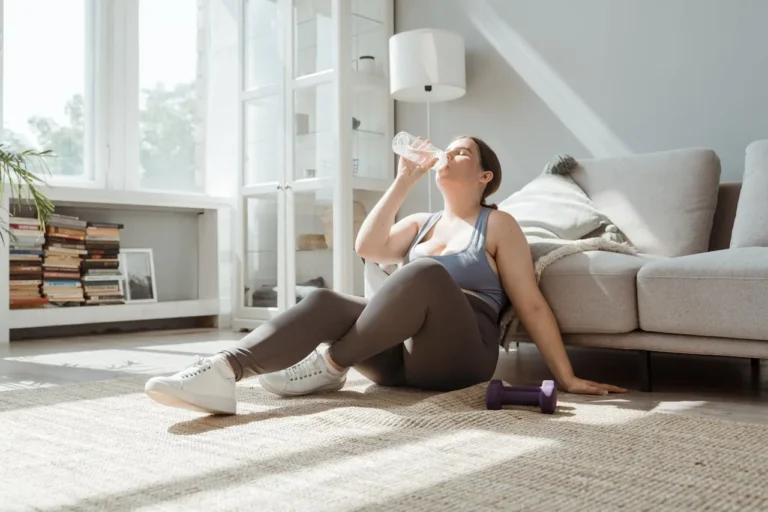 Woman doing home workout for natural weight loss with healthy foods nearby.