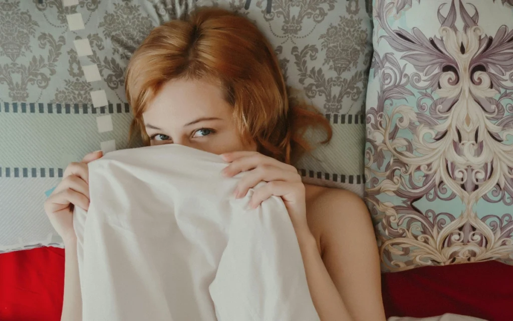 Calm woman lying under blanket on bed