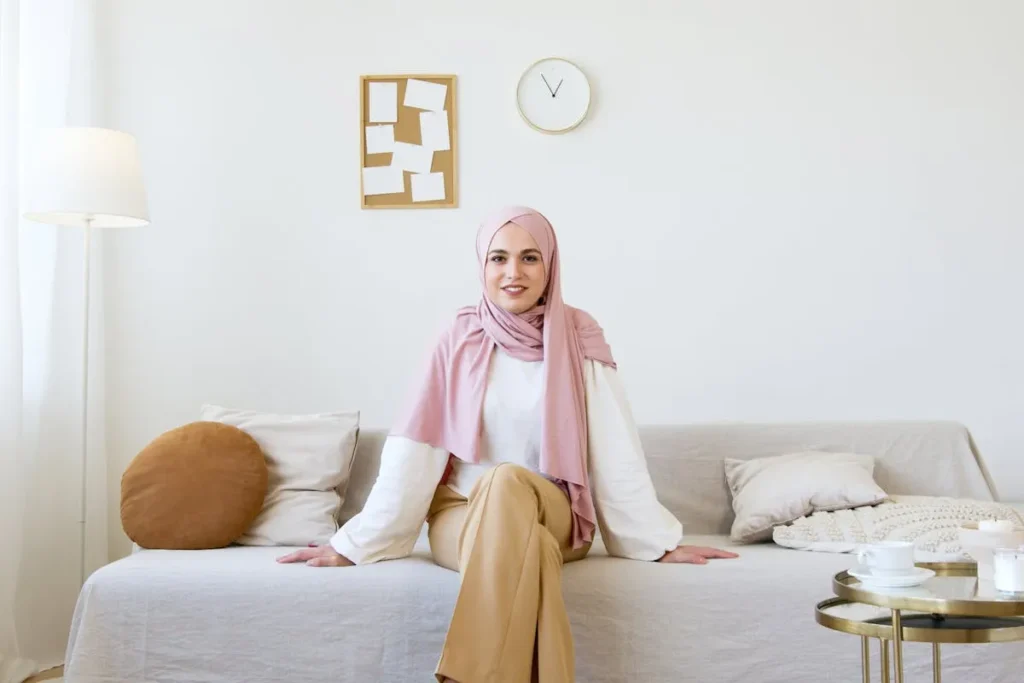 Muslim woman at home gently touching her belly, showing calm first trimester self-care and Islamic health practices