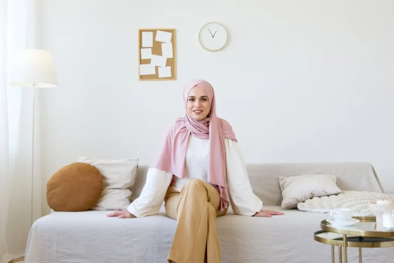 Muslim woman at home gently touching her belly, showing calm first trimester self-care and Islamic health practices